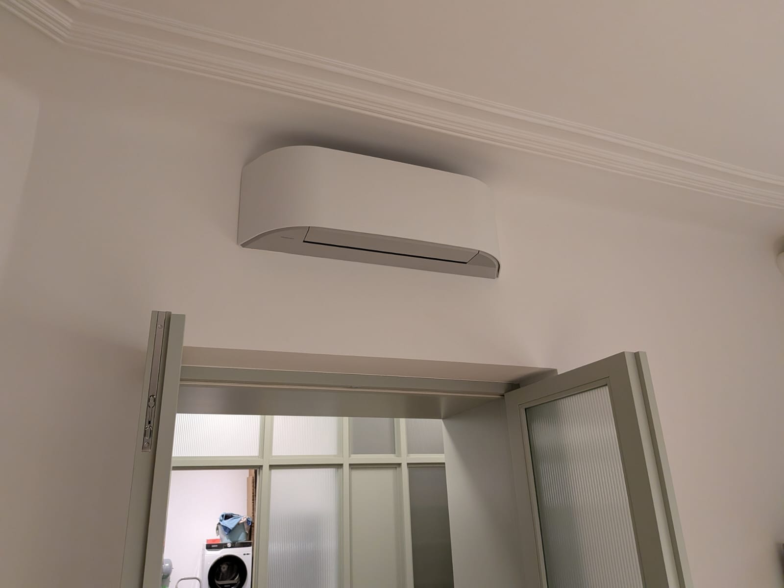 Reálná instalace TopKomfort - designová vnitřní jednotka klimatizace nad dveřmi pražského bytu